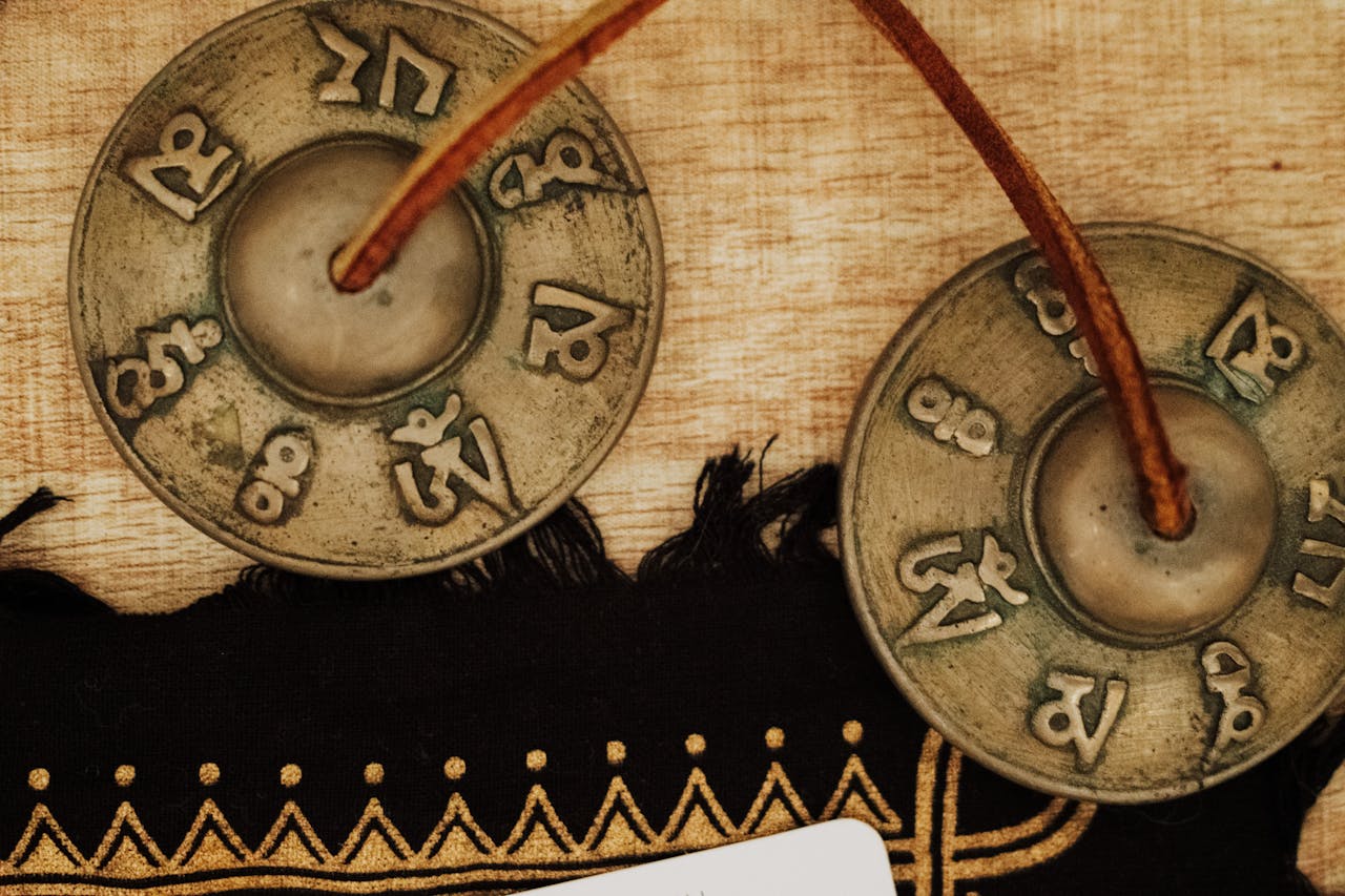 About Tibetan Tingsha cymbals with sacred symbols on decorative cloth.
